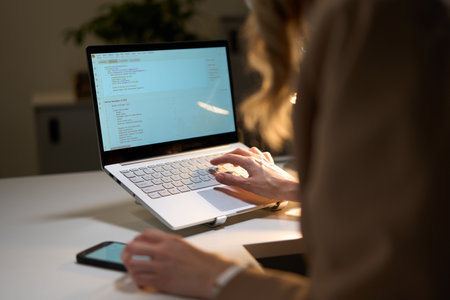 Person Working on a Laptop Analyzing Data in a Modern Office Environmentの写真素材