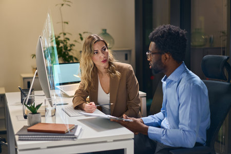 Two Professionals Collaborating and Discussing Innovative Ideas in a Modern Office Environmentの写真素材
