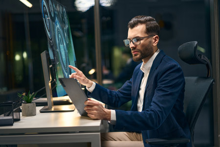 Professional Worker Using Digital Devices in Modern Office During Evening Hoursの写真素材