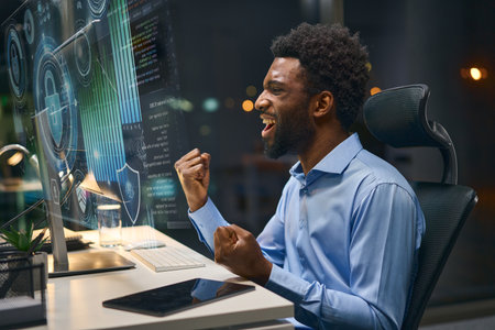 Cybersecurity Specialist Celebrating Successful System Solution in Modern Office Environmentの写真素材