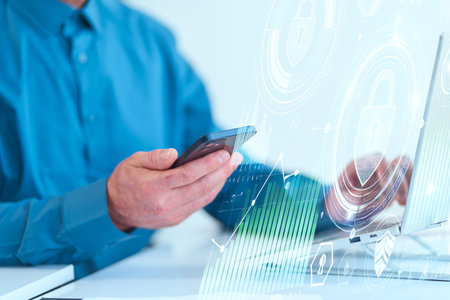 Businessman Using Smartphone And Laptop with Digital Security Icons in Modern Office
