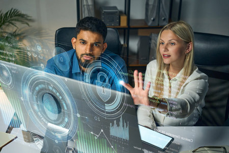 Two Professionals Evaluating Data on a High-Tech Transparent Display in an Officeの写真素材