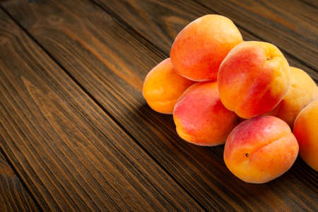 Apricots on wooden background. Fresh juicy apricots piled on a wooden table. Close-up healthy organic food.の写真素材
