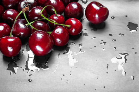 Wet ripe juicy sweet cherries on a black plate. Lots of wet fresh cherries with water drops. Close-up of many cherries.の写真素材