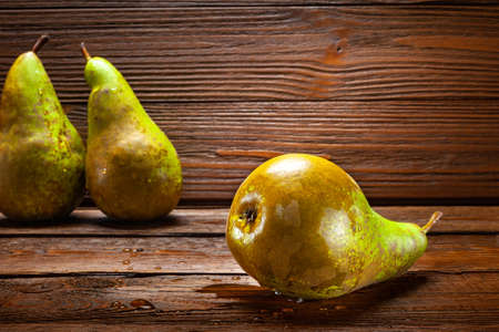 Ripe wet pears with drops of water on a dark wooden background. Organic foods, healthy nutrition.の写真素材