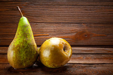 Two ripe wet pears with drops of water on a dark wooden background, space for text. Organic foods, healthy nutrition.の写真素材
