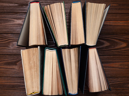 Old books. Top view of a group of old used an open book with hard cover in dust on dark wooden...