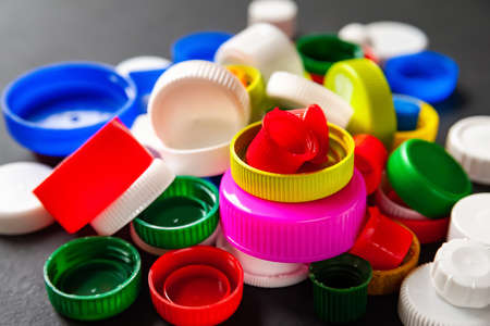 Close-up of colored PET caps on a black background. Recycled plastic bottle caps. Separate garbage collection. Recycling of plastic for prosthetics. Selective focus. Multicolored texture.の写真素材