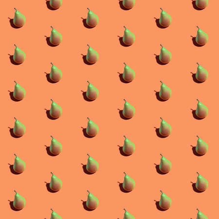 Colorful seamless pattern of fresh pears on a orange background. Fresh ripe organic pears isolated on a orange surface. Vegan, vegetarian healthy food. Organic product. Autumn harvest.の写真素材