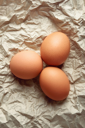 Chicken eggs. Top view of raw brown chicken eggs on crumpled wrapping paper. High calorie protein...