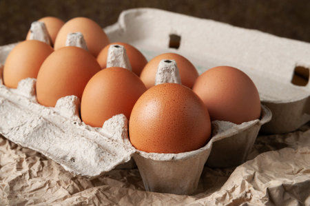 Chicken eggs in an egg box. Raw brown chicken eggs on crumpled wrapping paper. High calorie protein...