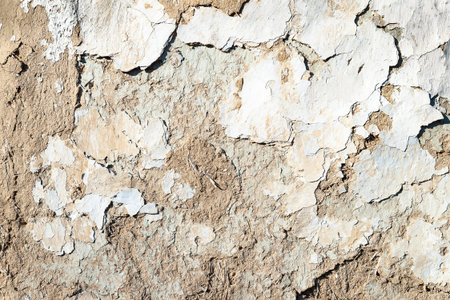 Old plastered wall background. The texture of the old peeling cracked, weathered plaster with chips...