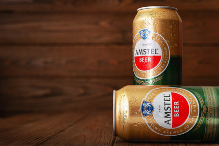 Beer cans with water drops. AMSTEL beer in cans covered with condensation. World famous Dutch brand. Wooden background with copy space. Selective soft focus. Kiev. Ukraine. June-26.2021.のeditorial素材