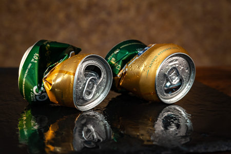 Wet beer cans. Two crumpled empty beer cans with water drops on brown background, close-up. AMSTEL...