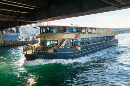 A tourist boat sails under the Galata Bridge in the Golden Horn Bay in Istanbul. Istanbul. Turkey - 09.25.2021.のeditorial素材