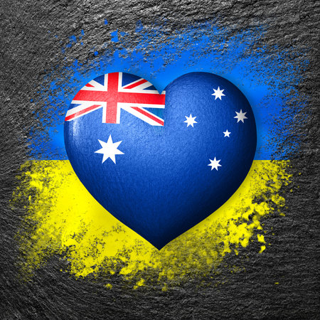 Flags of Ukraine and Australia. Flag heart on the background of the flag of Ukraine painted on a stone. The concept of protection and solidarity. military and humanitarian aid.の写真素材