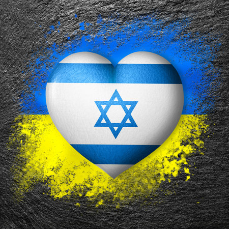 Flags of Ukraine and Israel. Flag heart on the background of the flag of Ukraine painted on a stone. The concept of protection and solidarity. military and humanitarian aid.の写真素材