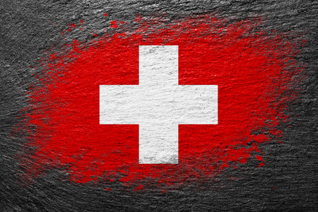 Flag of Switzerland. Flag is painted on a stone surface. stone background. Black slate background. creative backgroundの写真素材
