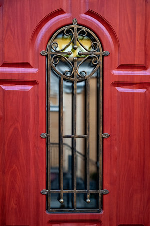 red door. Close-up of a red door with a window and bronze bars. selective soft focusの写真素材