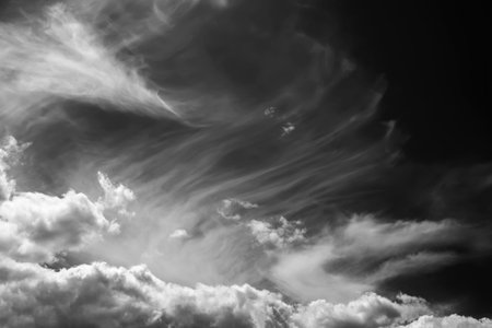 White clouds on a dark dramatic sky. Storm wind clouds. Black and white sky template to create...