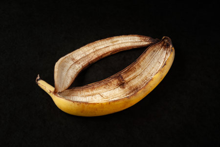 Banana peel on a black background. One over-ripe banana close-up. food wasteの写真素材