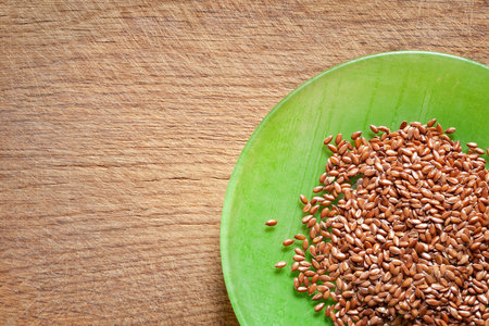 Flax seeds. Flax in a green bowl on a wooden board. Omega 3. Healthy food. View from aboveの写真素材