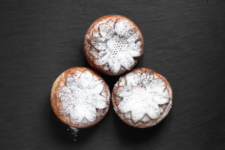 fresh muffins. Muffin sprinkled with icing sugar. Top view of muffins on a dark textured background....