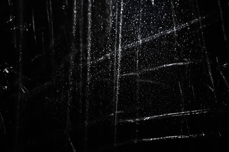 Abstract background. The shine of crumpled polyethylene. Synthetic glitter on black. Selective focusの写真素材