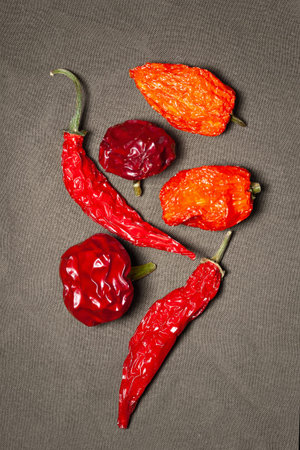 Hot pepper. Mix of peppers. Dry hot peppers stacked on fabric background. Top view. Selective soft...