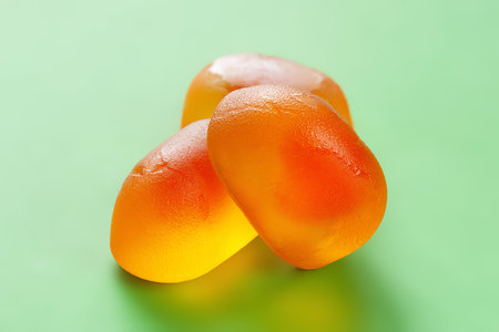Jelly candies. Set of orange jelly candies close-up. Green candy backgroundの写真素材