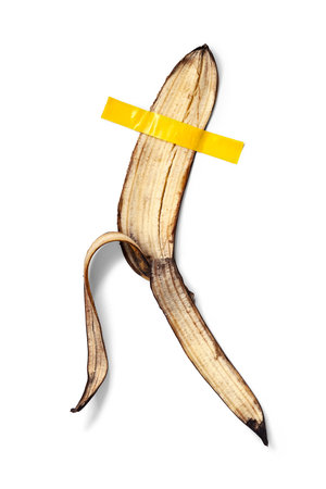 Yellow banana peel glued with yellow tape. Isolated on white background. Conceptual photoの写真素材
