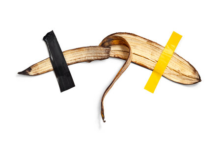 Banana peel glued with tape. Isolated on white background. Conceptual satirical photoの写真素材
