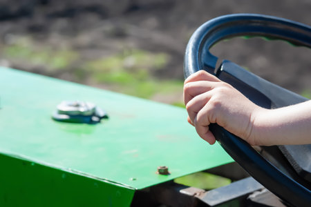 Hands on the steering wheel. The kid holds the steering wheel of the tractor. Selective soft focusの写真素材