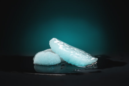 Ice melting. Melting ice chunks on dark background. Colored backlight. Selective soft focusの写真素材