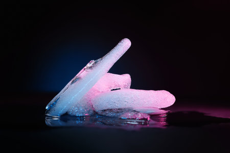 Ice melting. Melting ice chunks on dark background. Colored blue-purple backlight. Selective soft...