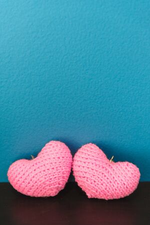 Two pink of crochet hearts on black wood board and blue vintage backgroundの写真素材