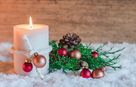 Traditional Advent and Christmas candle with ornament and decoration on snow with wood background,...
