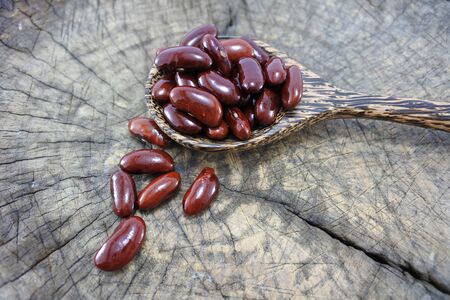 Red beans in a wooden spoon on wood backgroundの写真素材