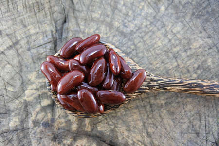 Red beans in a wooden spoon on wood backgroundの写真素材