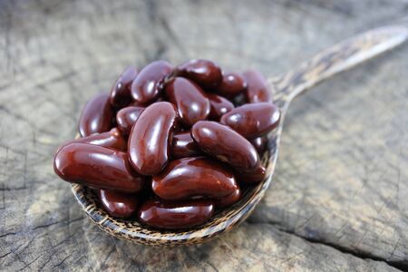 Red beans in a wooden spoon on wood backgroundの写真素材