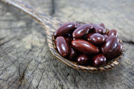 Red beans in a wooden spoon on wood backgroundの写真素材