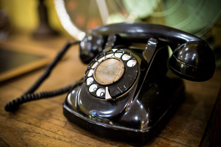 Old black phone was placed on wooden table.