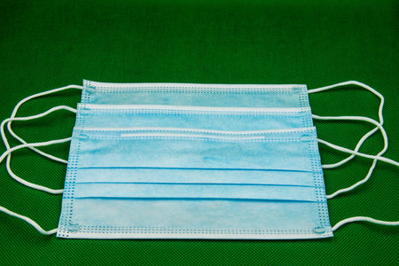 Three blue face masks on the green floor.