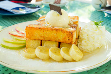 Toast and ice cream are placed on top, paired with bananas and apples.の写真素材
