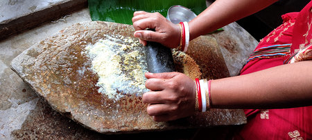 Traditional Indian way of grinding spices(yelloe mustard) with the grinding stone in ancient age...