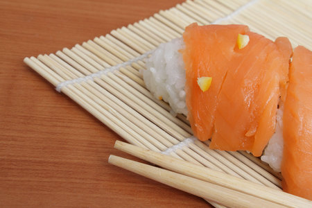 Closeup  of salmon sushi and chopsticks on bamboo matの写真素材
