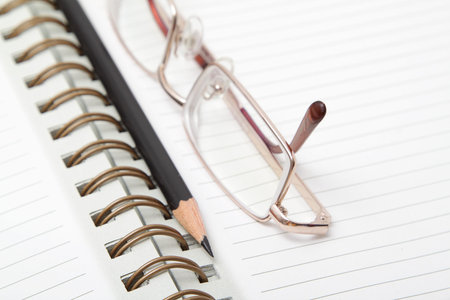 A diary, a black pencil and the reading glasses 
