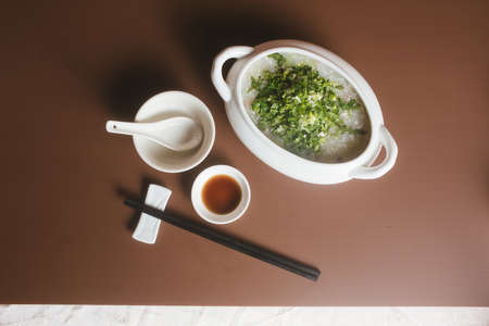 Rice porridge with chopsticks and soy sauce on brown backgroundの写真素材