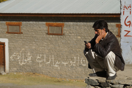 A Pakistani man looking at his cellphone,Northern Pakistanのeditorial素材
