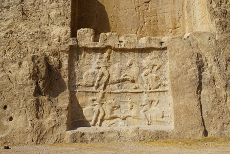 Ancient relief of the necropolis Naqsh-e Rustam that shows the equestrian victory of Bahram II over enemy, near ruins of Persepolis.の写真素材